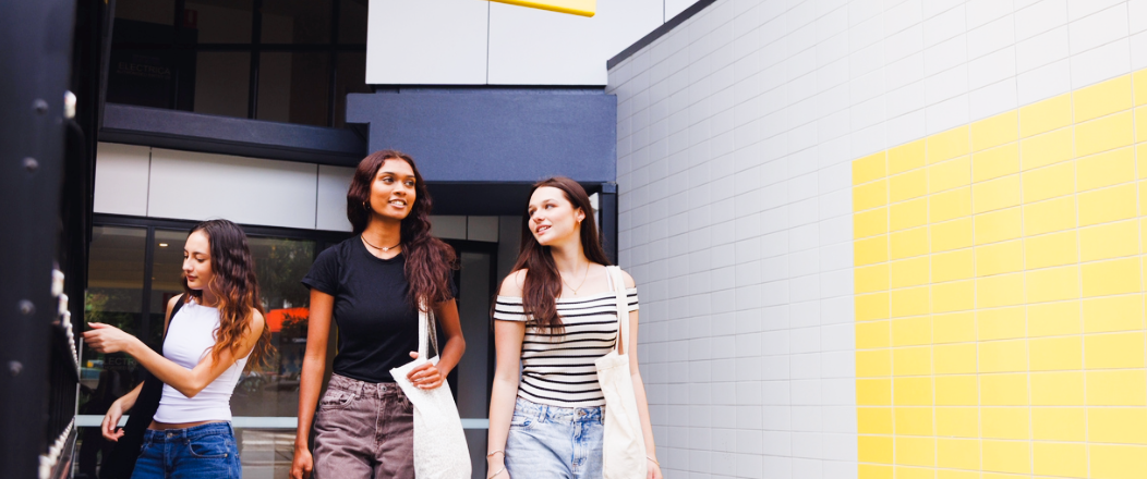 Three university students gathering outside a student accommodation walking to class.